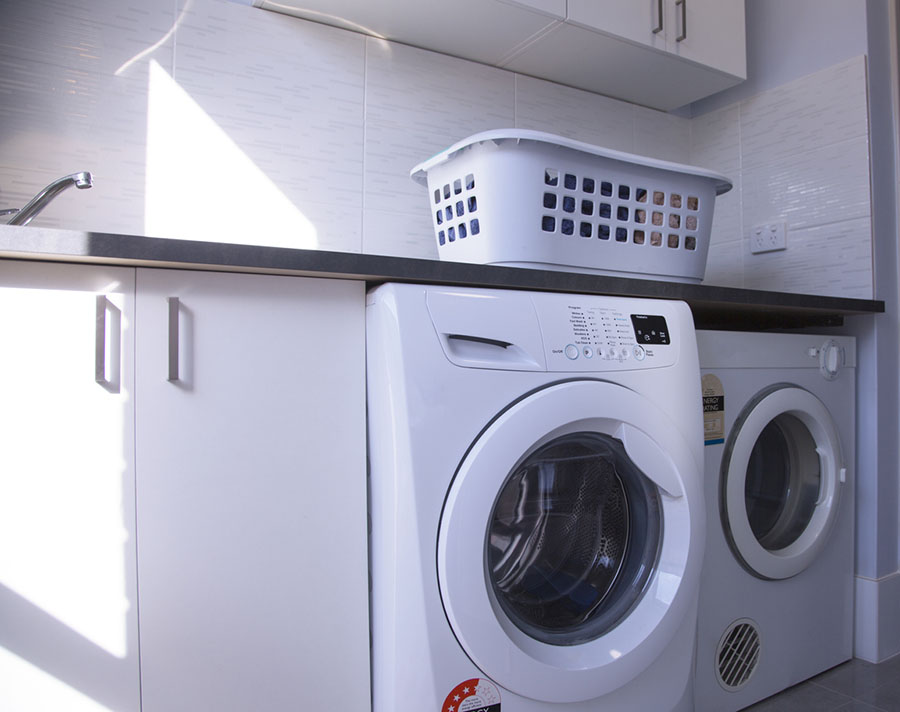 An Australian home laundry with washing machine, clothes dryer and washing basket.